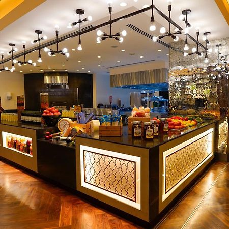 Jabal Omar Hyatt Regency Makkah Hotel Mekka Eksteriør billede The photo shows a stylish and modern buffet area in a restaurant or hotel. The design features a sleek counter with various food items displayed, including fresh fruits. The space is well-lit with pendant lights hanging from the ceiling, creating a w