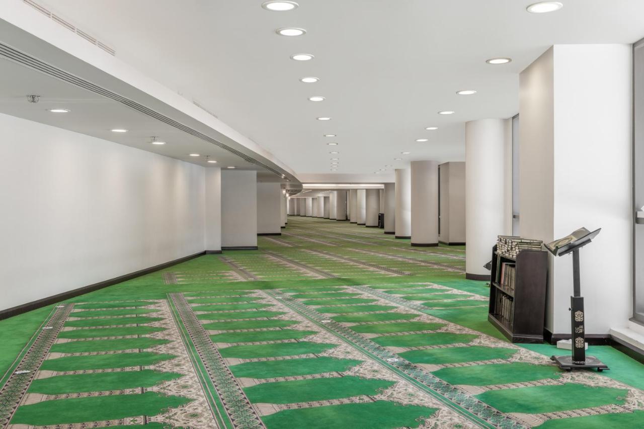 Jabal Omar Hyatt Regency Makkah Hotel Mekka Eksteriør billede The photo shows a spacious, well-lit indoor area with a green carpet designed for prayer. The carpet features a decorative pattern and outlines spaces where individuals would pray. There are white walls and several light fixtures in the ceiling provi