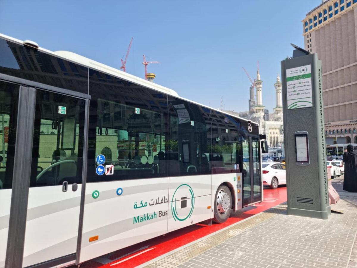 Jabal Omar Hyatt Regency Makkah Hotel Mekka Eksteriør billede The photo shows a public bus labeled "Makkah Bus," parked at a designated bus stop. The bus has a modern design and is predominantly white, with green accents. In the background, there are tall buildings and construction cranes, indicating a busy urb