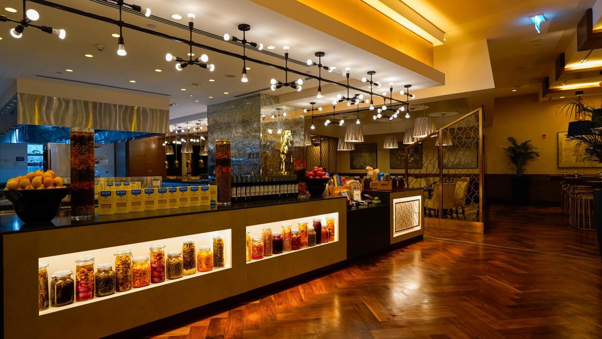 Jabal Omar Hyatt Regency Makkah Hotel Mekka Eksteriør billede The photo shows a stylish interior of a restaurant or café. It features a well-lit space with modern lighting fixtures hanging from the ceiling. The focal point is a counter area with jars filled with colorful ingredients or snacks, illuminated by li