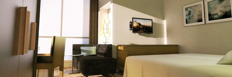 Jabal Omar Hyatt Regency Makkah Hotel Mekka Eksteriør billede The photo shows a modern hotel room or living space featuring a small seating area. On the left, there is a dark-colored couch and a glass side table. Across from the couch, mounted on the wall, is a flat-screen television. The room has light-colored