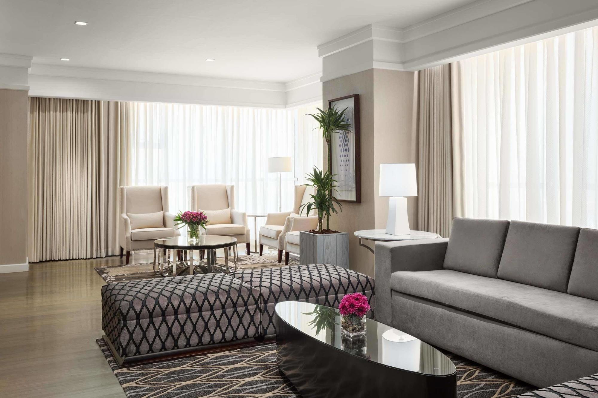 Jabal Omar Hyatt Regency Makkah Hotel Mekka Eksteriør billede The photo depicts a modern living room with a stylish and inviting design. There are large windows covered with light-colored curtains that allow natural light to fill the space. The furniture includes a gray sofa, a patterned ottoman with a geometri