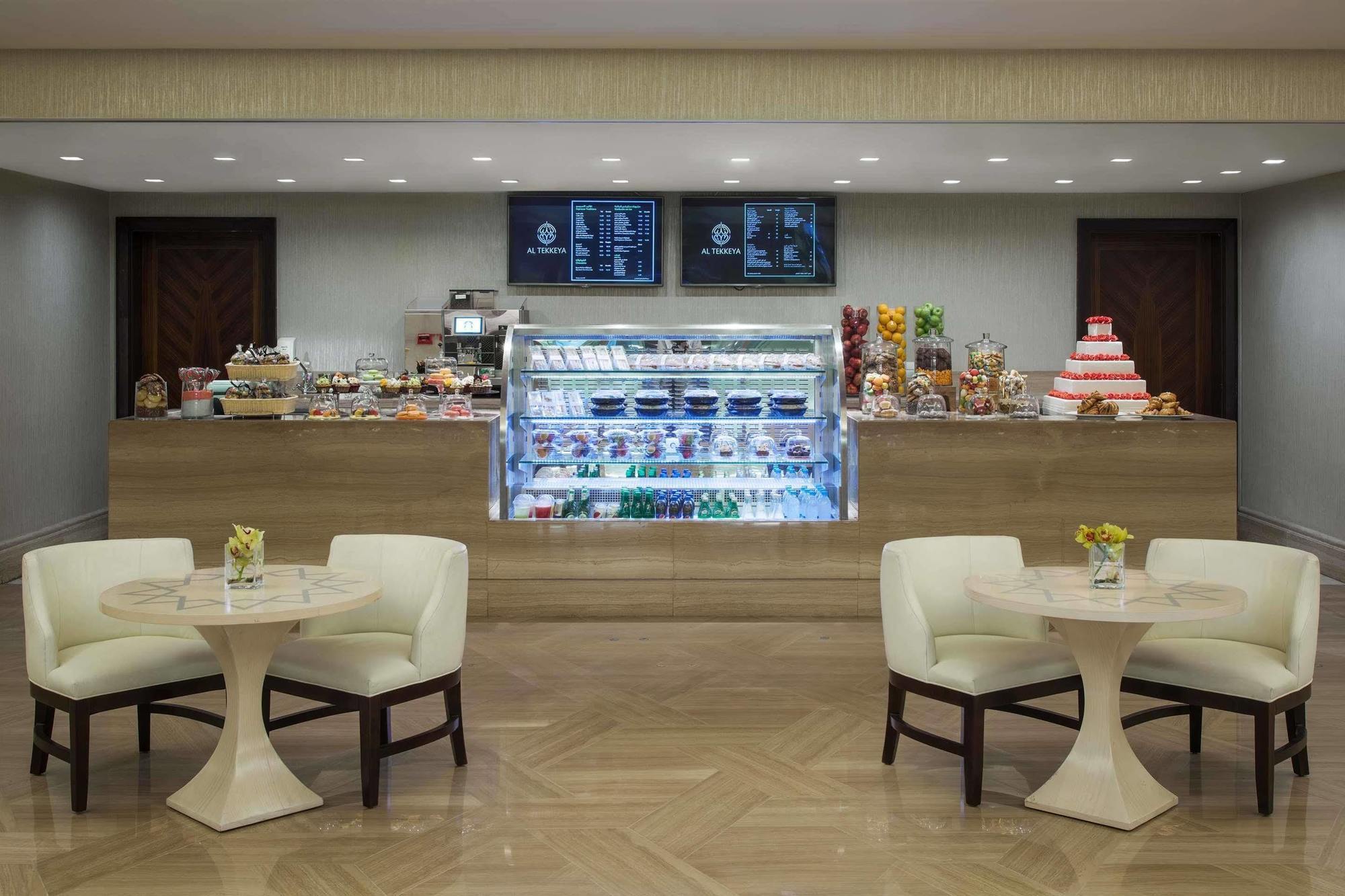 Jabal Omar Hyatt Regency Makkah Hotel Mekka Eksteriør billede The photo shows a quaint café or dessert shop interior. In the background, there's a neatly arranged counter displaying a variety of pastries and desserts, including cakes and sweets. Above the counter, two menus or screens display the offerings. In 
