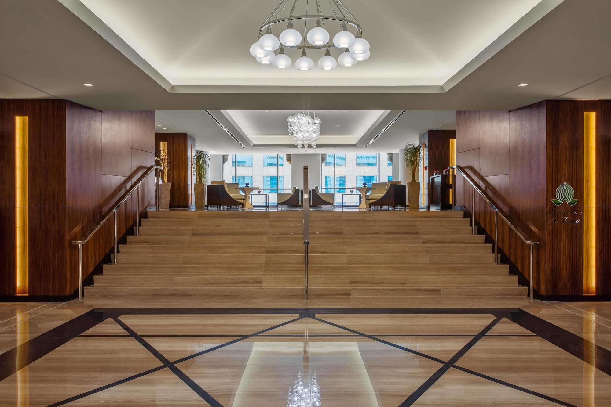 Jabal Omar Hyatt Regency Makkah Hotel Mekka Eksteriør billede The photo depicts a modern and elegant lobby area. There is a wide staircase made of wood that leads up to another level, flanked by stylish seating on both sides. The lobby features a combination of wooden and marble flooring, with a geometric patte