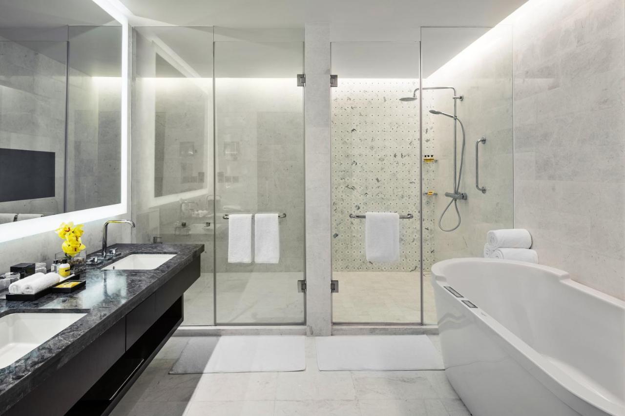 Jabal Omar Hyatt Regency Makkah Hotel Mekka Eksteriør billede The photo shows a modern bathroom with a sleek design. It features a glass shower enclosure with a rainfall showerhead and a stylish bathtub. The floor and walls have a light-colored stone or tile finish, giving a clean and minimalist look. There's a