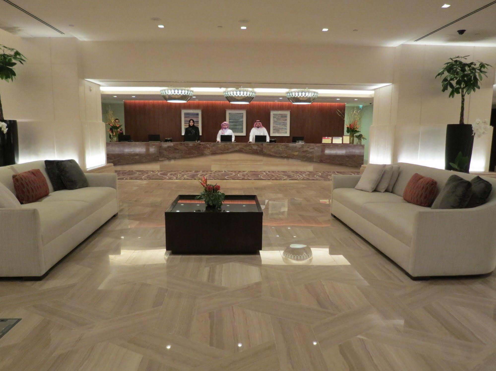 Jabal Omar Hyatt Regency Makkah Hotel Mekka Eksteriør billede The photo shows a modern hotel lobby. In the foreground, there are two light-colored sofas with decorative pillows, positioned facing each other. A small coffee table with a plant sits between the sofas. 

In the background, there is a reception desk